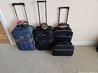 Photo of four carry-on luggage pieces standing side by side against a wall, each equipped with a telescoping handle and luggage straps placed on top.