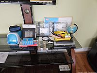 Wide shot showing all office supplies including label maker, clock, tape measure, globe, magnifying glass, stapler, and various boxes