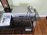 Phillips 4 head hi-fi stereo DVD and video player with remote and paper instructions displayed on glass table.