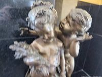 Close-up front angle showing the faces and upper bodies of the two children on the brass statue.