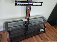 Full view of the TV stand showing the smoked glass shelves and the black base.