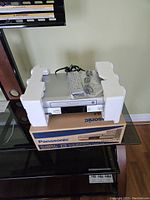 Panasonic VHS player still held by foam protection on sides, resting on its original box, remote and cables placed on top.