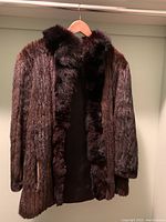 Front view of brown mink jacket with fox fur trim on collar and front edges, showing plush and glossy fur texture.