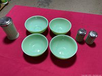 Four jadeite bowls and three matching shakers on red background.