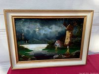 Full view of framed reverse painted glass art showing windmill, house, river, and sky.