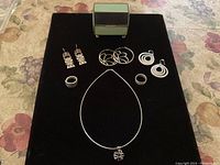 All jewelry pieces and vintage jewelry box displayed on black fabric showing entire lot layout.