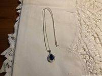 Full view of the sterling silver necklace with pendant on a white cloth background.