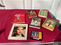 Six books on a red tablecloth, titles include Oz 75th Anniversary and Rainbow: The Story Life of Judy Garland.