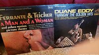 Photo showing two albums: Ferrante & Teicher 'A Man and a Woman' and Duane Eddy 'Twangin' The Golden Hits' with visible cover art of couple kissing and musician with guitars.