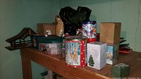 Photo showing a variety of Christmas storage and decorative items on a wooden table against green walls.