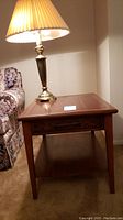 Wood end table with smooth top, basket weave design on apron, lower shelf, warm brown finish