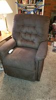 Front view of an olive green textured fabric power recliner and lift chair, showing cushioned back with button tufting, padded armrests, and recliner controls on the side.