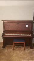 Full view of the Story & Clark upright piano with accompanying wooden stool with blue cushioned seat.