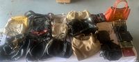 Photo showing a collection of assorted purses, clutches, and wallets laid out showing variety of colors and sizes.