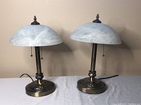 Two matching table lamps side by side with frosted dome-shaped glass shades and brass bases.