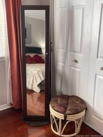 Full view of the jewelry cabinet closed showing the full-length mirror on the front and dark wood finish.