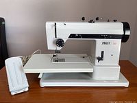 Full profile photo of the PFAFF 297 white sewing machine with attached work surface and foot pedal on the left side of image