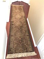 Full view of the runner rug laid on hardwood floor, showing its length and fringed end.