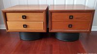 Front view of both teak bedside tables side by side on red hardwood floor.