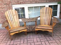 Front view of two wooden Adirondack chairs connected by a slatted side table