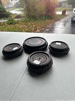 Four Chinese wooden carved round display stands placed on white surface with outdoor background showing their size and shape.