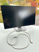 Front view of the 27-inch Monoprice monitor powered off, showing screen and power cord coiled in front.