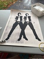 Full view of the poster on a table outdoors showing the doubled Han Solo figure in black ink on a white background.