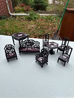 Photo showing miniature Chinese traditional style dollhouse furniture including sofa with missing arm, several chairs, and two tables all with white inlay decoration.