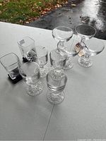 Photo showing all the glasses together on white table with natural outdoor lighting, glasses arranged in groups for clarity.