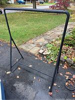 Front and side angled photos showing the black metal clothing rack with triangular base supports and damage at the joint between the base and one leg.