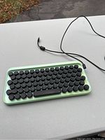 Compact Bluetooth keyboard with round vintage style keys on a light green base showing discoloration.