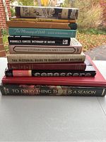 Stack of 11 books showing spines and some covers, includes titles related to knitting, nature, literature