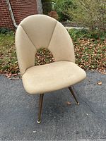 Front view of beige vinyl Mid-Century Modern swivel chair with curved backrest and four tapered metal legs.