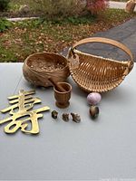Photo of lot items showing 2 woven baskets, brass decorative character, painted eggs, wooden mortar and pestle, and 3 small figurines.