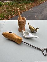 Photo showing all four items: wooden mortar with pestle, brass bird, ceramic feeder, and wooden shoe stretcher.