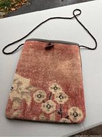 Front view of rectangular bag made from vintage Turkish rug material with floral patterns and a button flap closure.