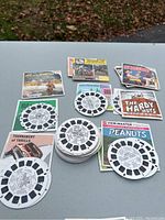 Top view of multiple View-Master reels laid out with accompanying booklet covers on a flat surface, showing several different themed reels and booklets.