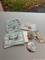 Overall image showing vintage Christmas cards and three distinct ornaments on a table.