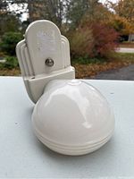 White porcelain wall lamp with dome shade placed in front and a lamp base without shade next to it, showing overall look and style.