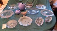 Full lot overview showing assorted servingware including vintage Hall China Rose Parade ceramics and various cut glass bowls and trays on a green cloth.