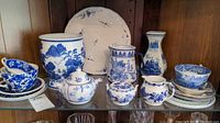 Shelf display of assorted blue and white china including plates, pitchers, bowls, cups, and saucers with traditional and floral patterns.