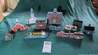 Full view of all 13 collectible wooden houses and decorative miniatures including red barn, white church, school building, riverboat, and signs