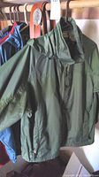 Green L.L. Bean jacket hanging on rack with belts