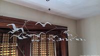 Side view of metal seagull mobile hanging from the ceiling, showing white seagulls in flight.