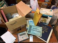 Overview image showing multiple boxes including one labeled "stamps" with envelopes, albums, and loose stamps partially visible on a table.