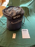 Blue AeroBed storage bag with instruction manual and tag on green background