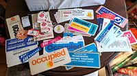 Photo showing a large assortment of airline seat cards and baggage tags from multiple airlines arranged on a table including various 'occupied' seat cards and 'reserved' signs in different colors and styles.