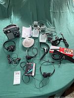 Full overview of vintage electronics assortment including radio receiver, cordless phones, CD and cassette players, headphones, cables, and antenna.