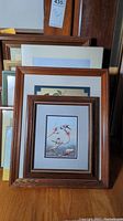 Photo shows several framed pieces of wall art stacked, revealing wooden and painted frames of varying sizes.