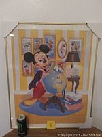 Framed print showing Mickey Mouse with globe and surrounding Mickey-themed artwork on wall.